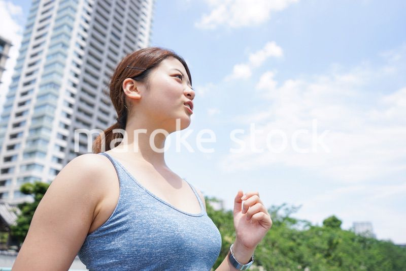 都会をランニングする若い女性