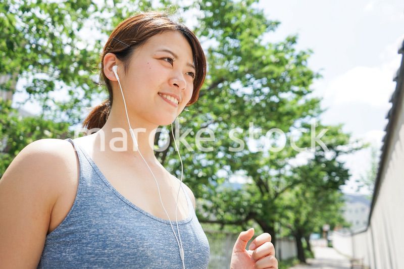音楽を聴きながらランニングする若い女性