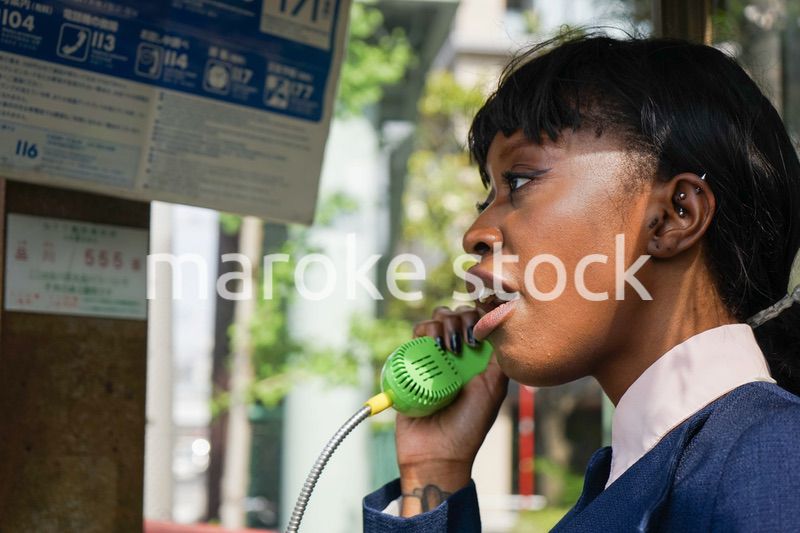 公衆電話で電話をする女性
