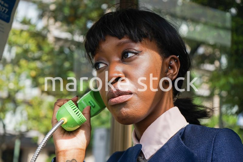 公衆電話で電話をする女性