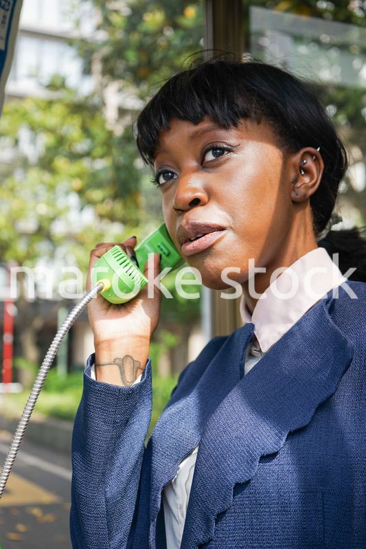 公衆電話で電話をする女性