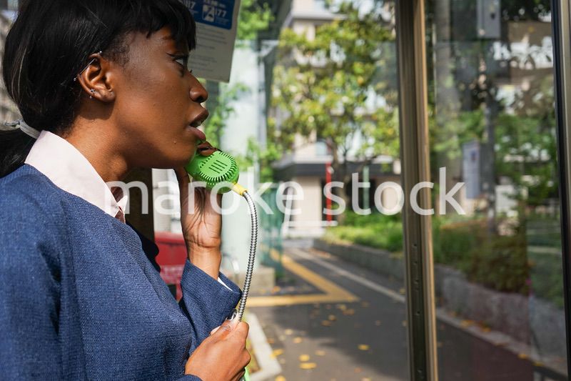 公衆電話で電話をする女性