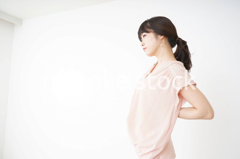 腰の痛みを感じる若い女性