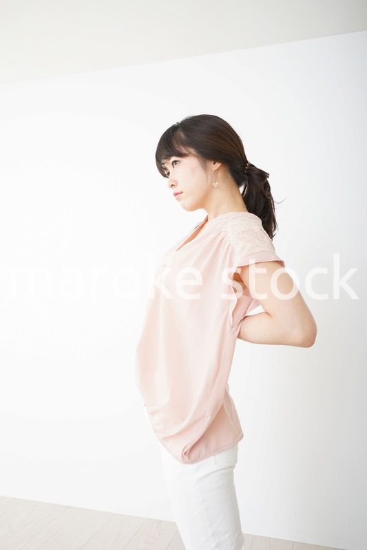 腰の痛みを感じる若い女性