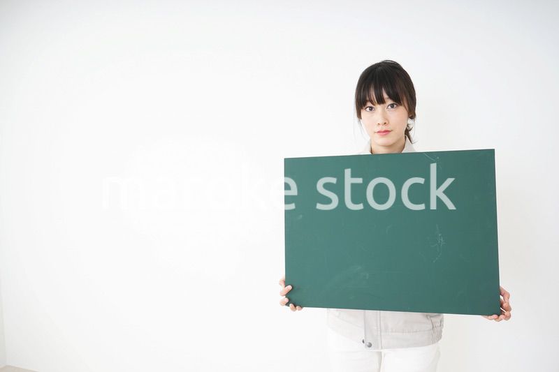 黒板を持つ作業服姿の女性