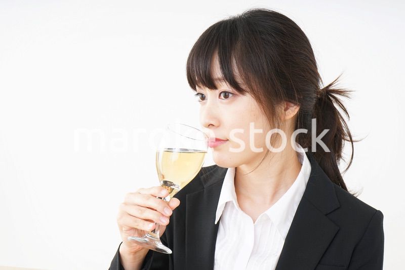 スーツ姿でお酒を飲む若い女性