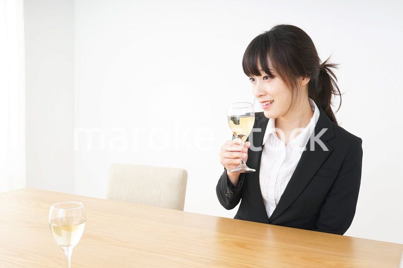 スーツ姿でお酒を飲む若い女性