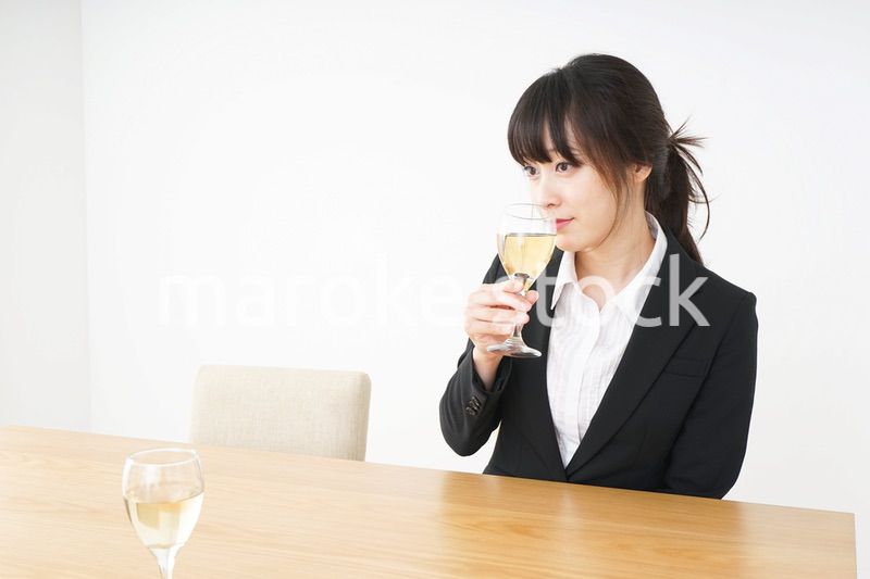 スーツ姿でお酒を飲む若い女性