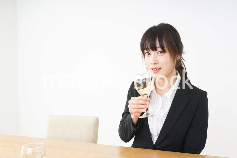 スーツ姿でお酒を飲む若い女性
