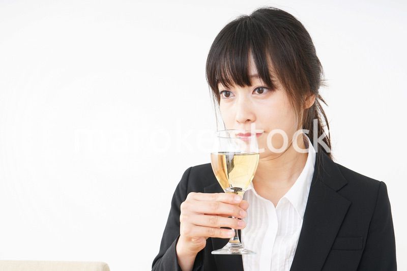 スーツ姿でお酒を飲む若い女性