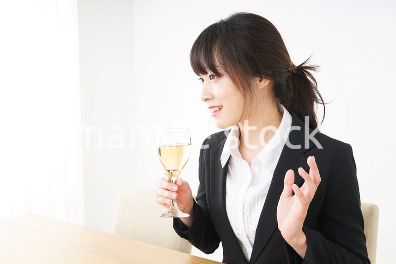 スーツ姿でお酒を飲む若い女性