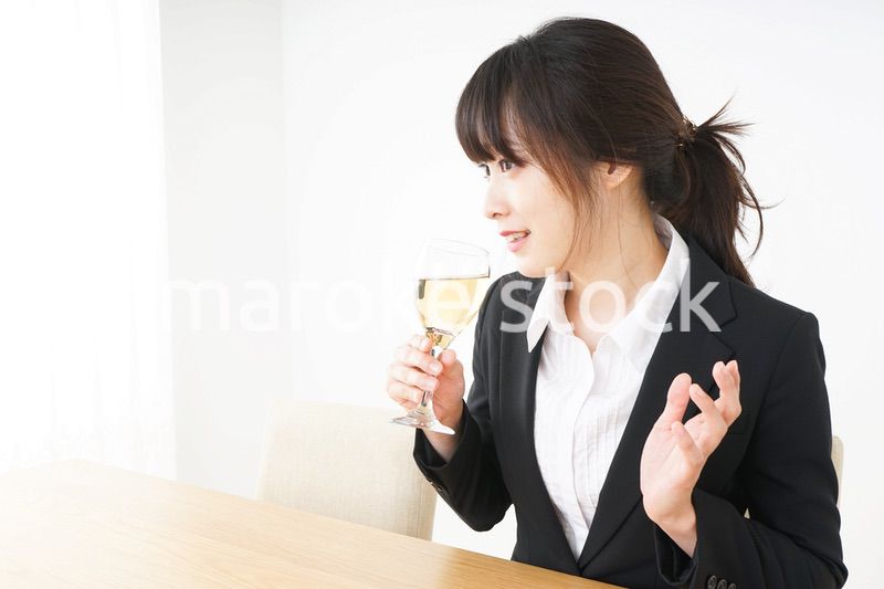 スーツ姿でお酒を飲む若い女性