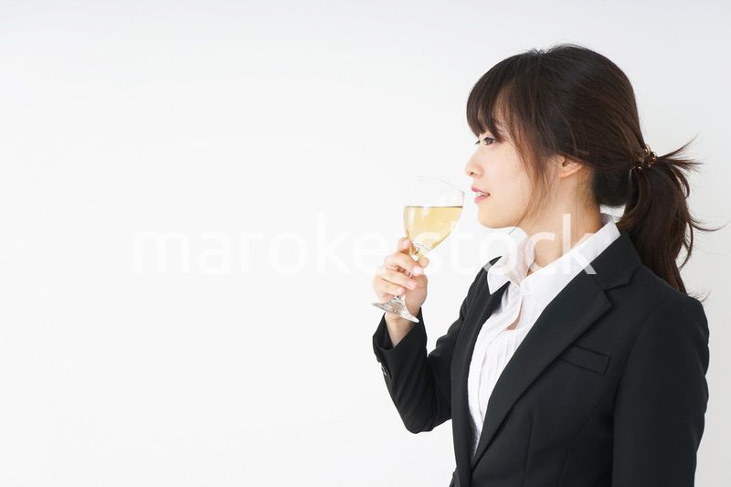 スーツ姿でお酒を飲む若い女性