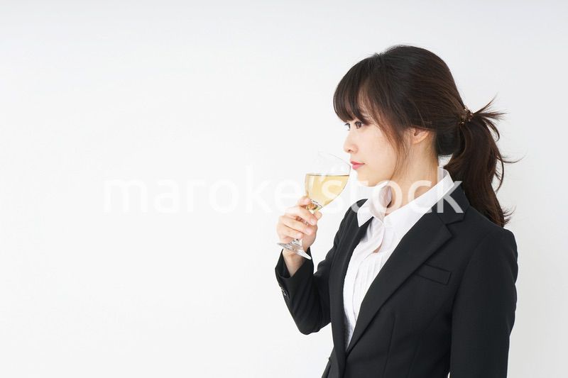 スーツ姿でお酒を飲む若い女性