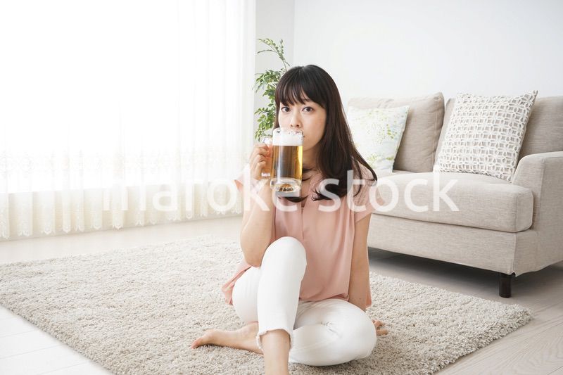 自宅でビールを飲む若い女性