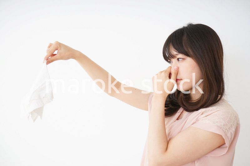臭い洗濯物の匂いを嗅ぐ若い女性