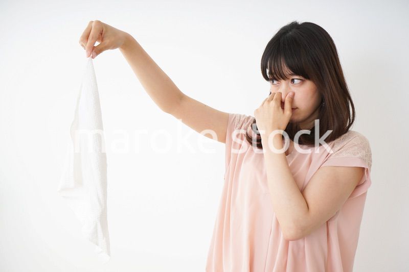 臭い洗濯物の匂いを嗅ぐ若い女性