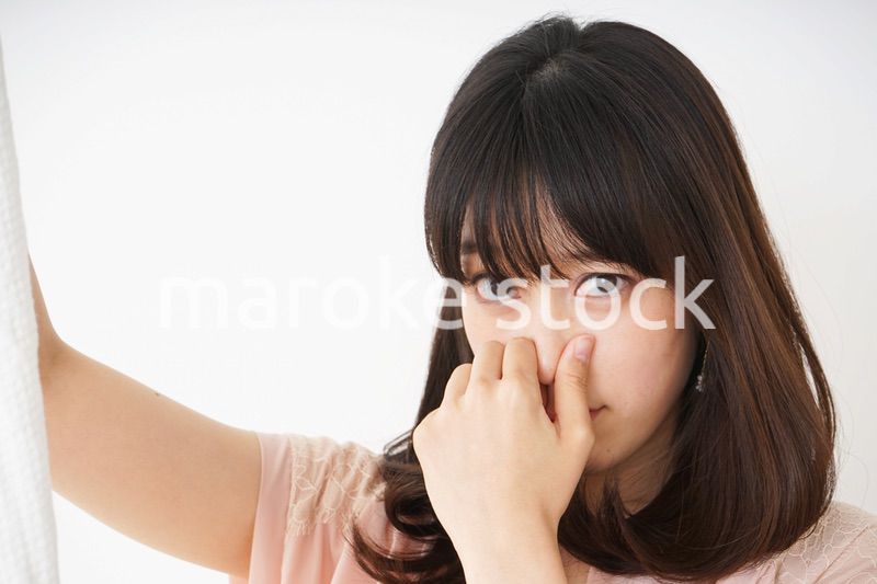 臭い洗濯物の匂いを嗅ぐ若い女性