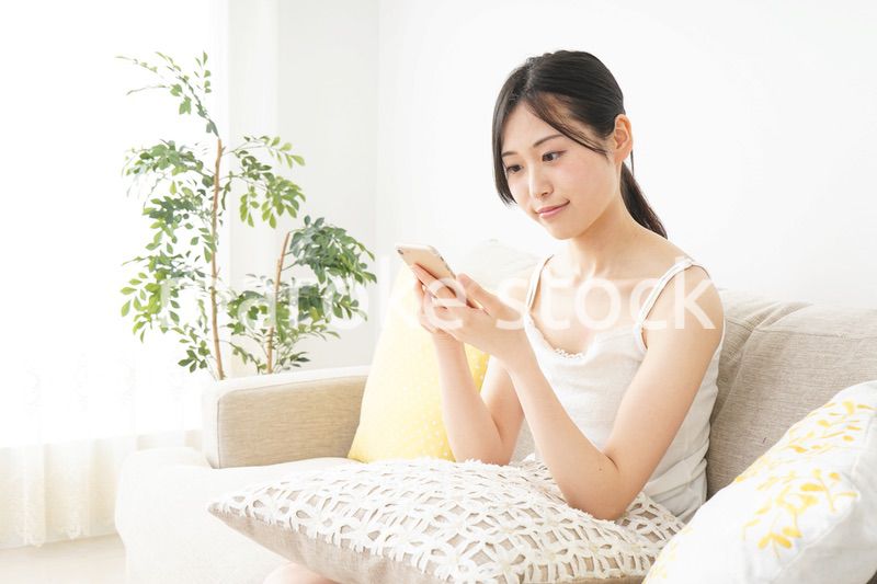 部屋でスマホを使う若い女性
