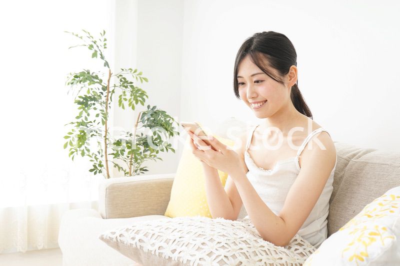 部屋でスマホを使う若い女性