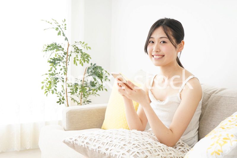 部屋でスマホを使う若い女性