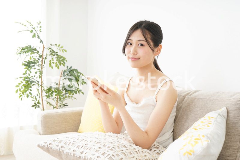 部屋でスマホを使う若い女性
