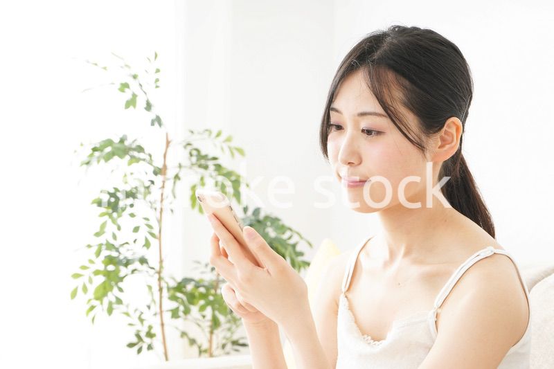 部屋でスマホを使う若い女性