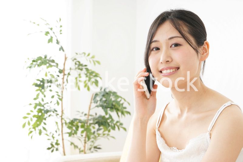 部屋でスマホを使う若い女性