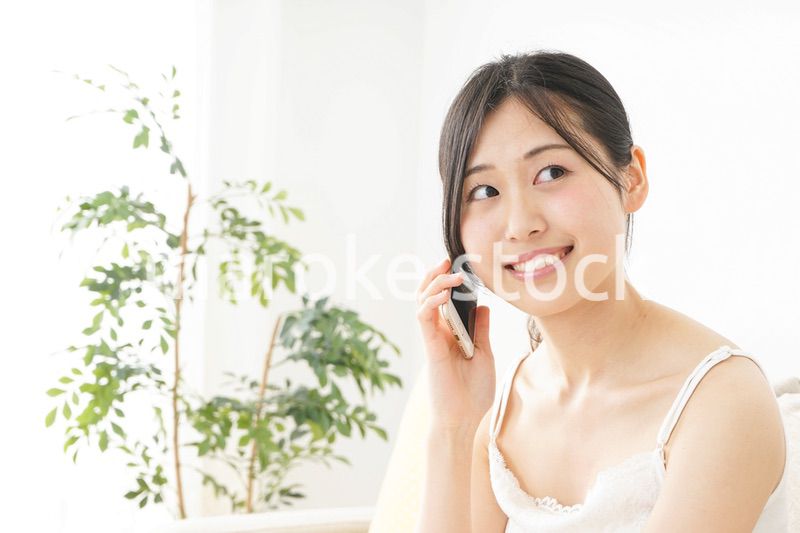 部屋でスマホを使う若い女性