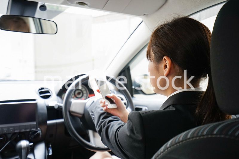 営業車で電話をするキャリアウーマン