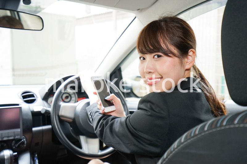 営業車で電話をするキャリアウーマン