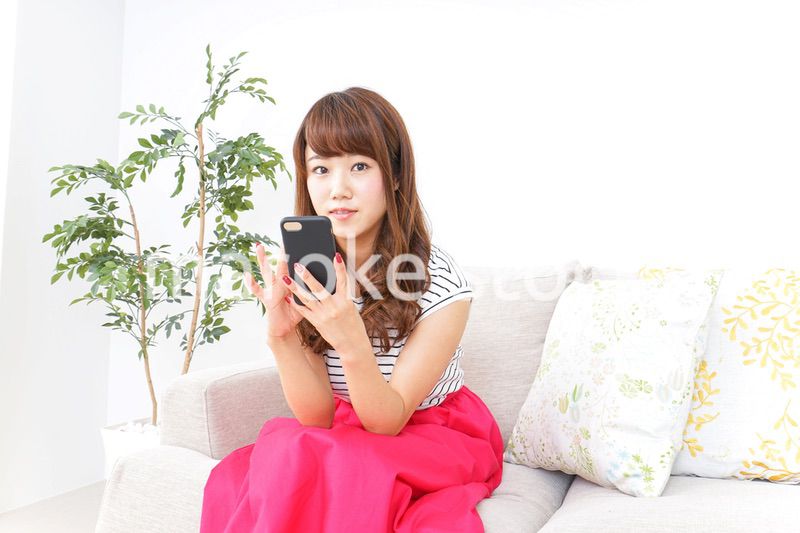 部屋でスマホを使う女性