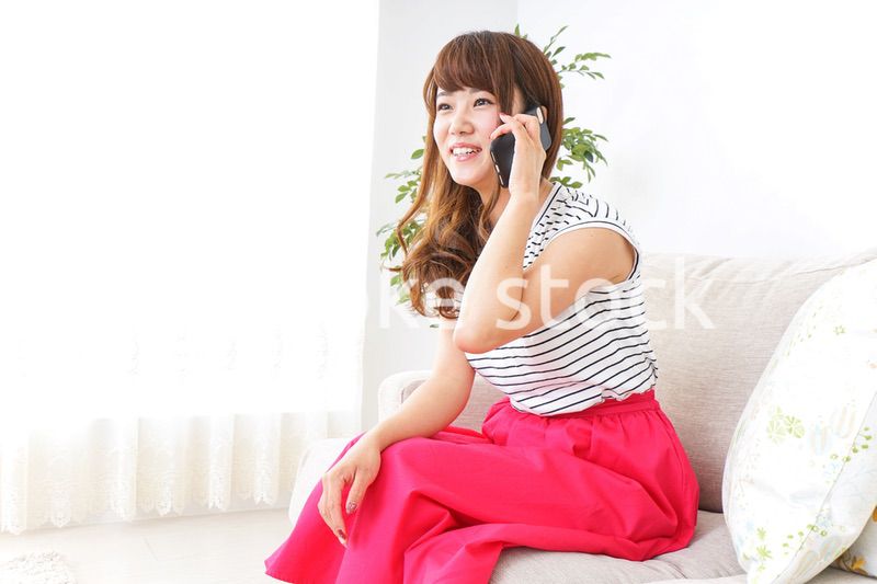 部屋でスマホを使う女性