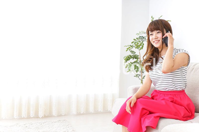 部屋でスマホを使う女性