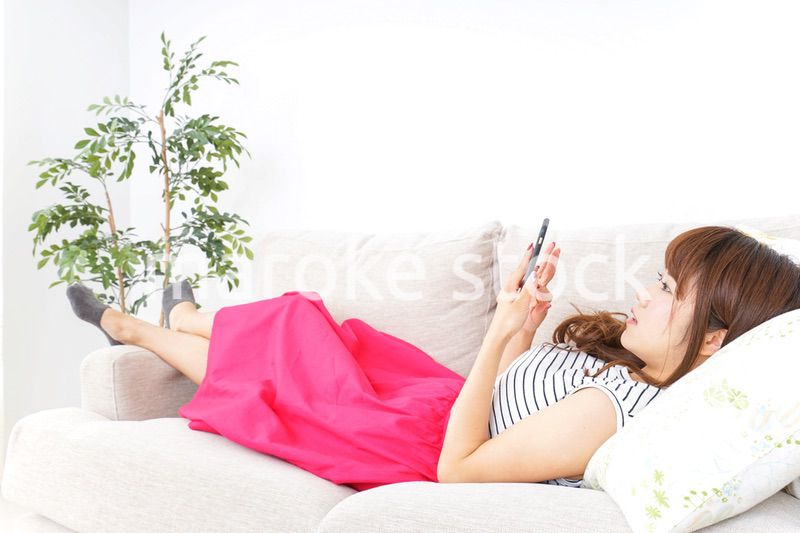 部屋でスマホを使う女性