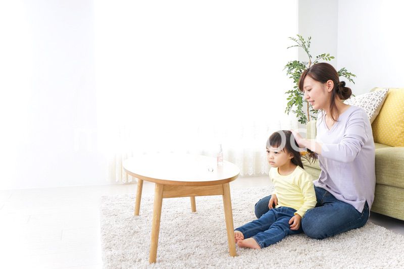 子どもの髪の毛を結ぶお母さん