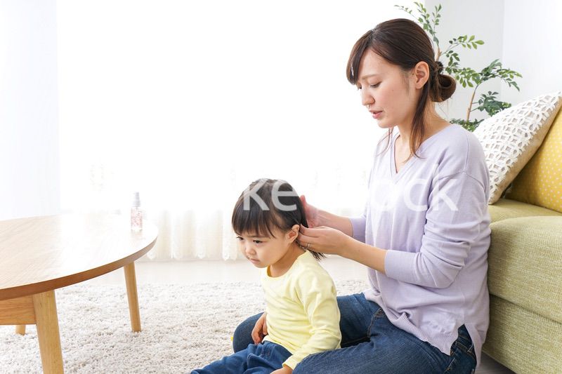 子どもの髪の毛を結ぶお母さん