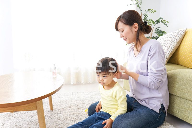 子どもの髪の毛を結ぶお母さん