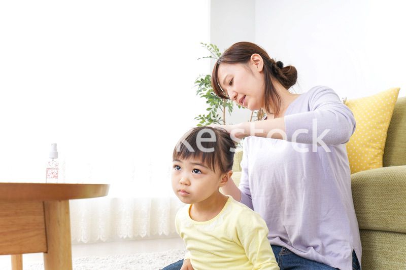 子どもの髪の毛を結ぶお母さん