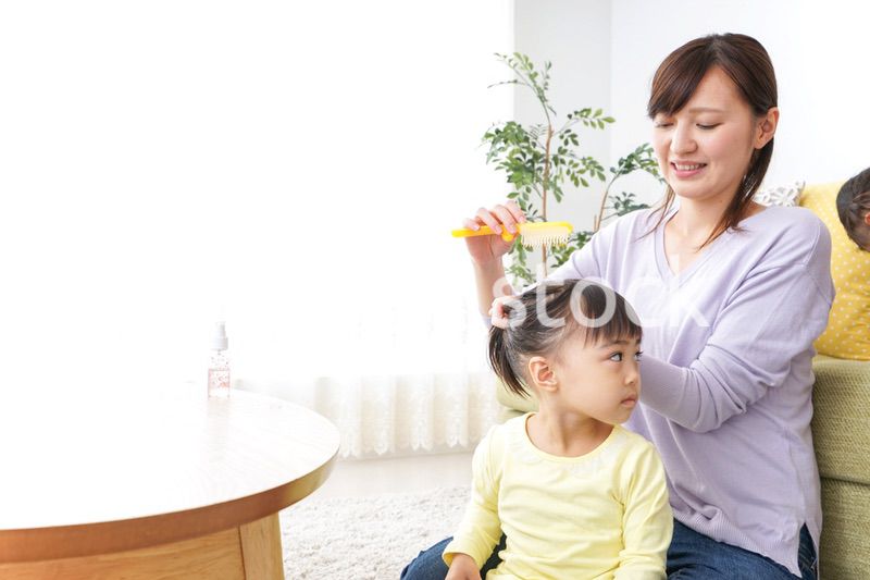 子どもの髪の毛を結ぶお母さん