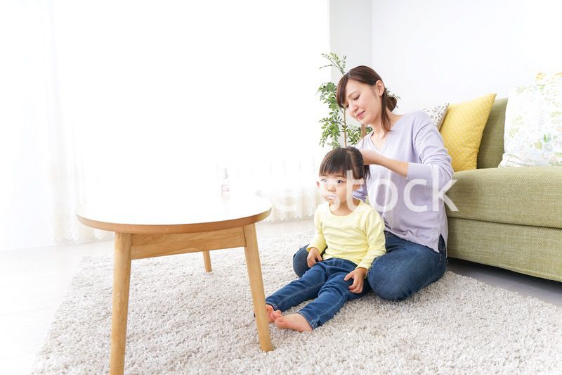 子どもの髪の毛を結ぶお母さん