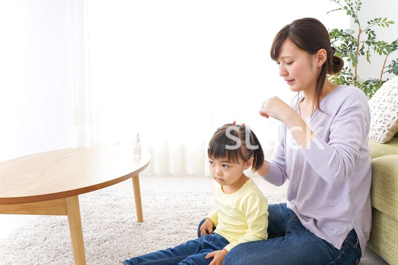 子どもの髪の毛を結ぶお母さん