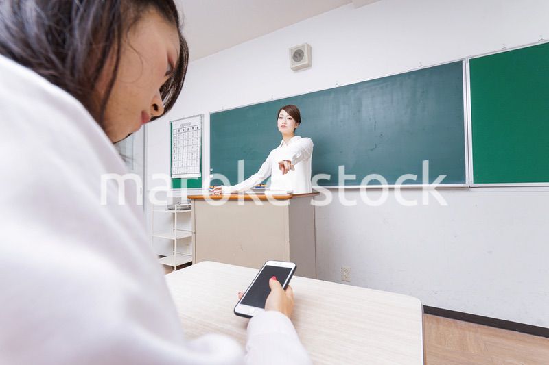 授業中にスマホを使う学生と注意する教師