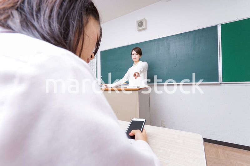 授業中にスマホを使う学生と注意する教師