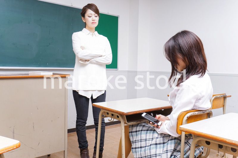 授業中にスマホを使う学生と注意する教師