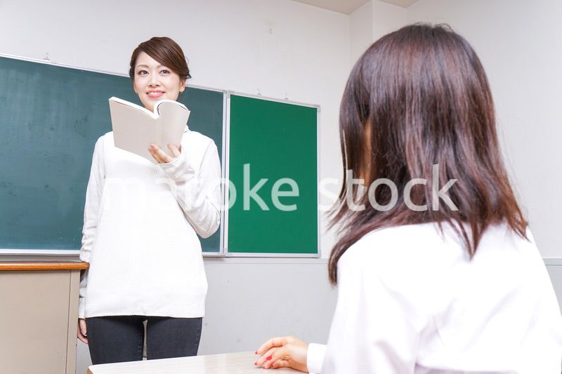 本を持って授業をする女性教師