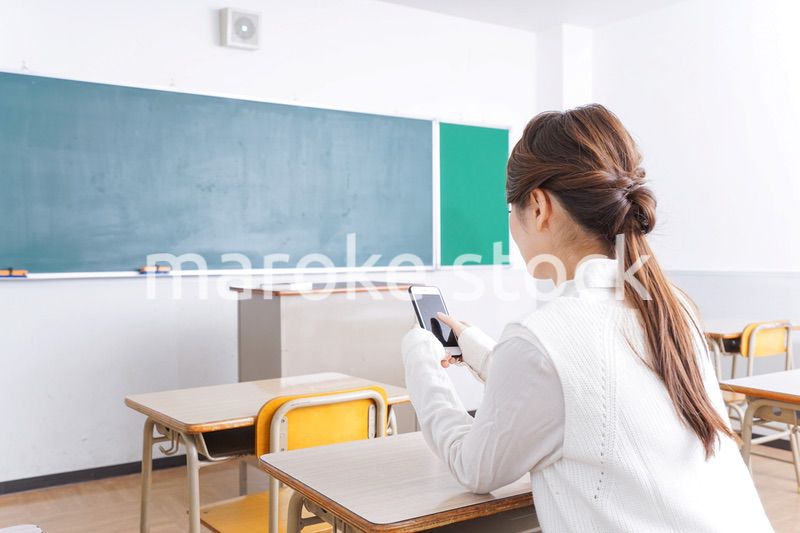 教室で携帯電話を使う学生