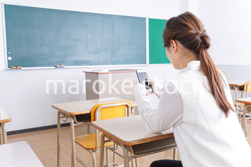 教室で携帯電話を使う学生