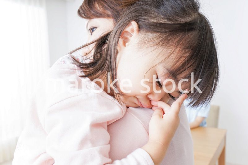 お母さんに抱かれて寝る子供