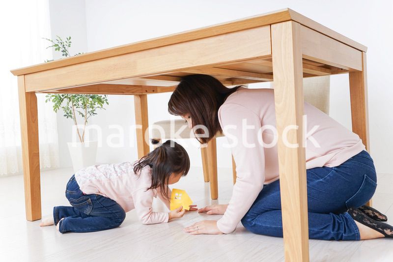 机の下に避難する親子